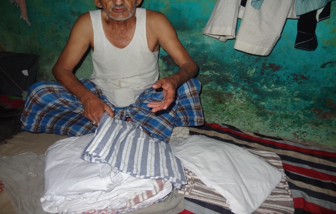 An elderly man folding garments